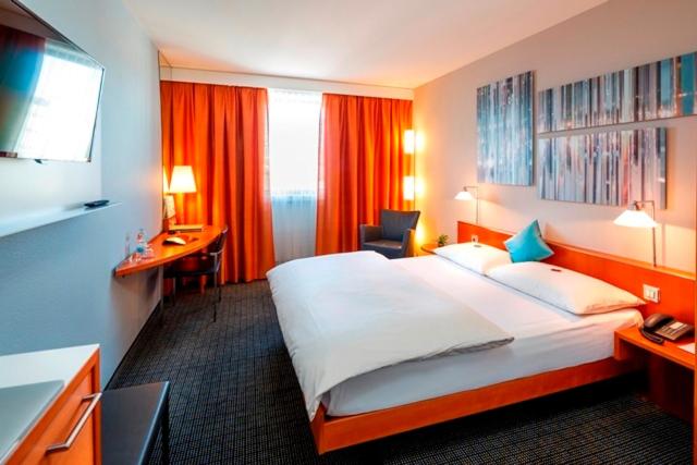巴塞尔Hotel Metropol Basel的酒店客房设有一张大床和一张书桌。