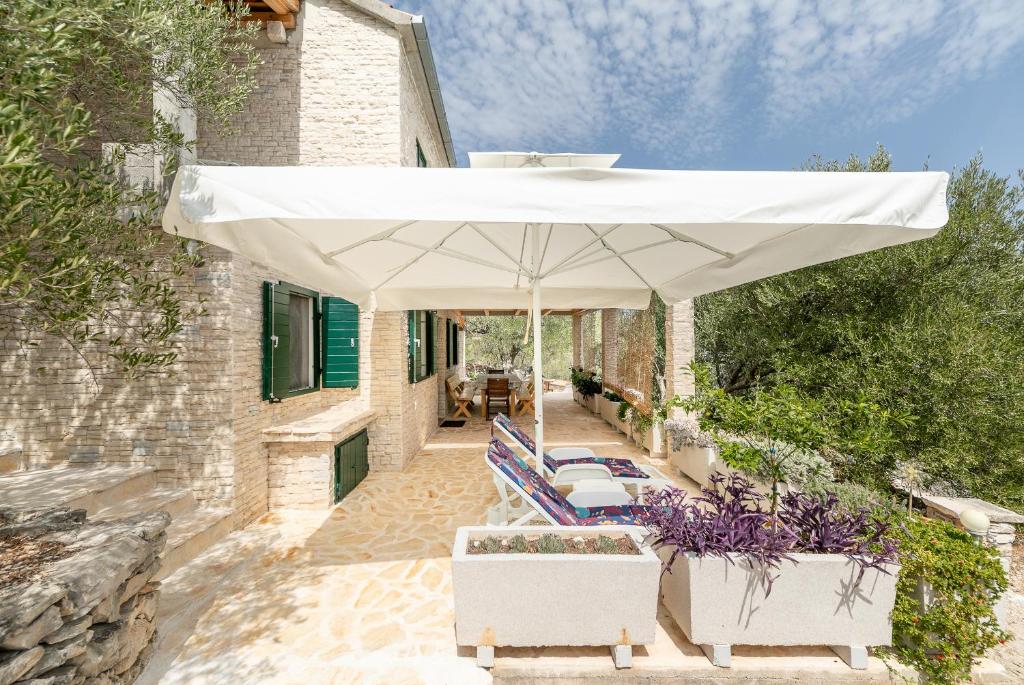 尼亚卢卡Villa Anita的庭院里配有白色遮阳伞、椅子和桌子