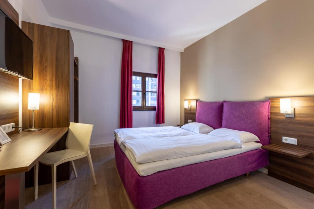 安特卫普Trip Inn Eden Antwerpen的一间卧室配有一张紫色的床和一张书桌