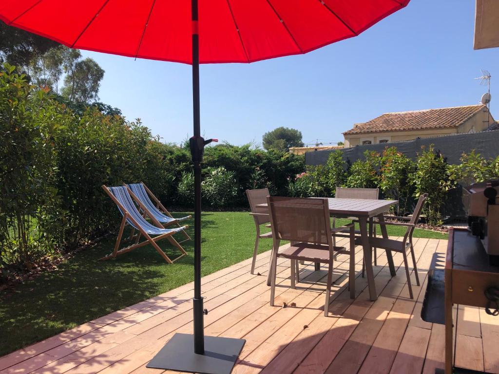 滨海萨纳里L'ete Indien 2的庭院里配有桌椅和红伞