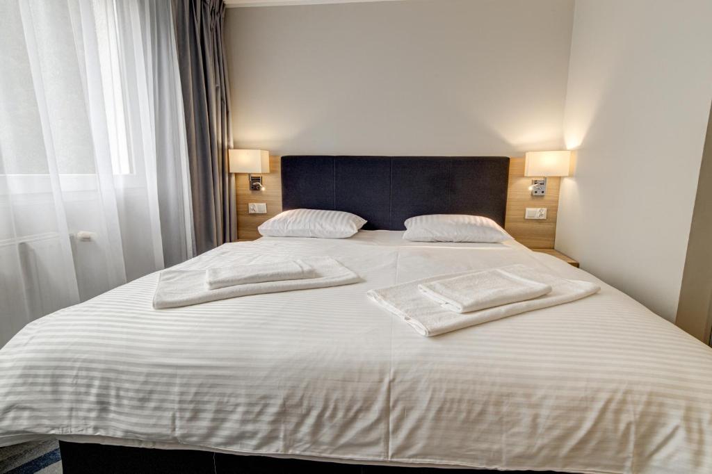 波利采多博思酒店的一张白色的大床,上面有两条白色毛巾