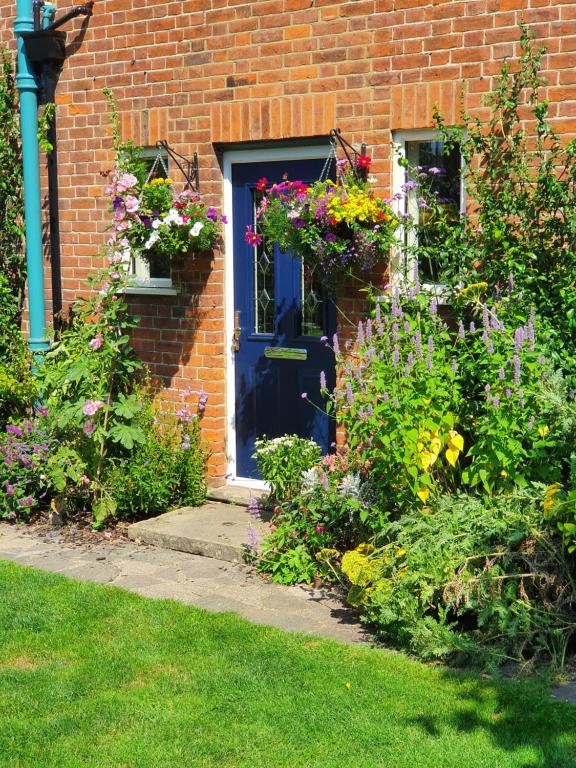 斯坦维尔The Lodge Stanwell的一座砖房,有蓝色的门和鲜花