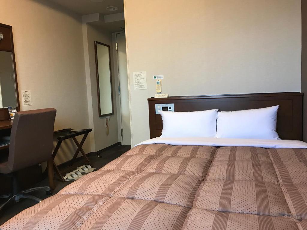 仙台仙台长町国际茹特酒店的一间卧室配有一张带白色枕头的床和一张书桌