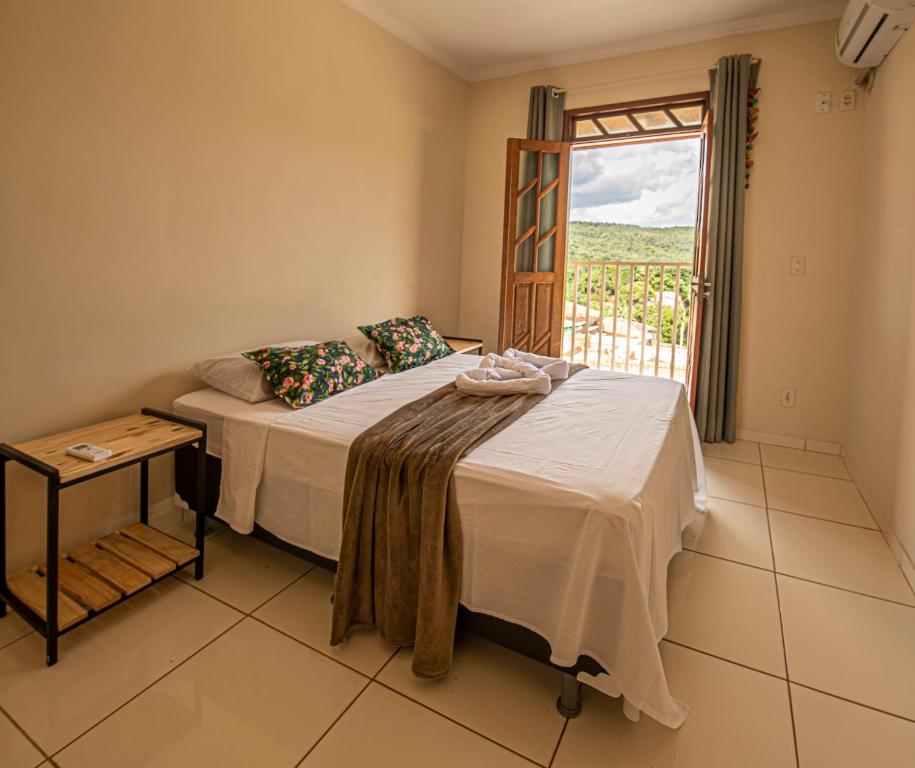 伦索伊斯Village Funchal, Lençóis的一间卧室配有一张带窗户和桌子的床