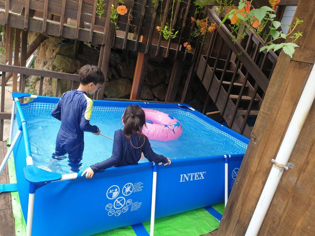 求礼郡吉利桑一晚两天度假屋的男孩和女孩在游泳池玩蹦床