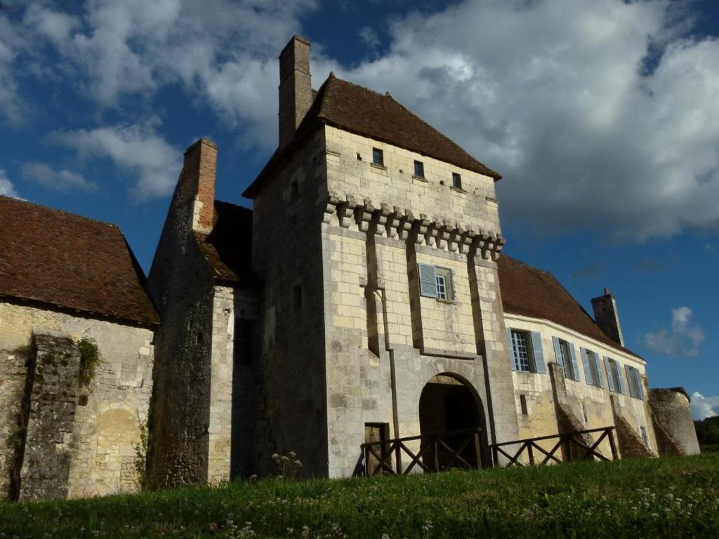 蒙特雷索Chateau-monastère de La Corroirie的一座古老的建筑,在草地上建有一座塔