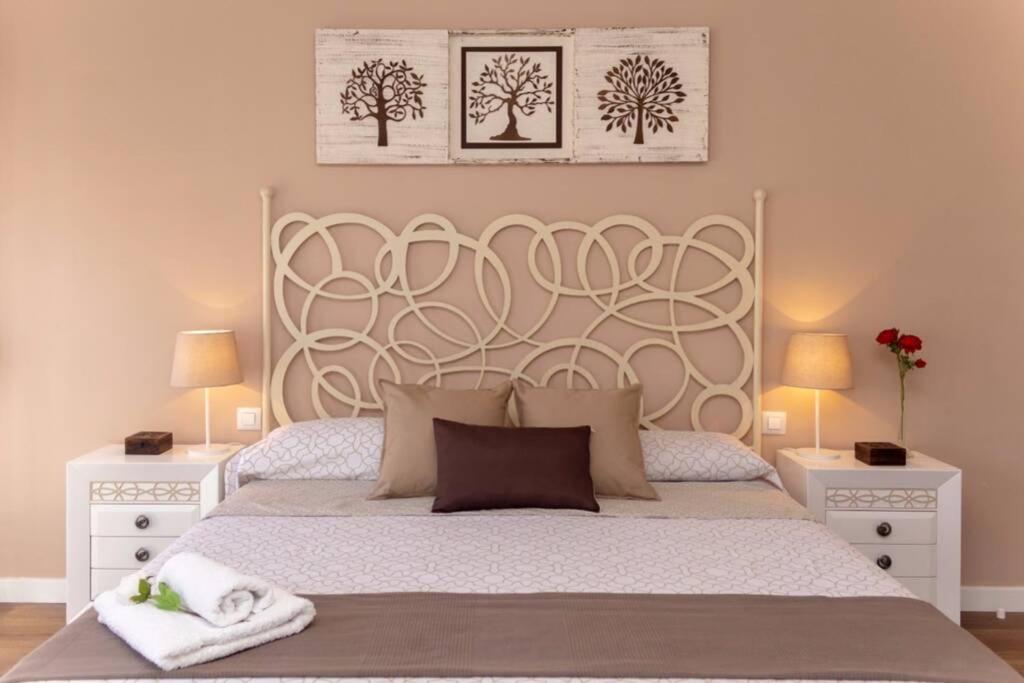圣马丁德拉韦加La Casa de Silvia Visita Parque Warner, Madrid y alrededores的一间卧室配有一张带2个床头柜的大型白色床