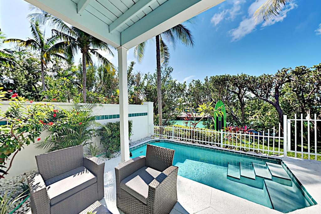 鸭礁岛Palm Villa的一座房子,设有游泳池、两把椅子和一个门廊