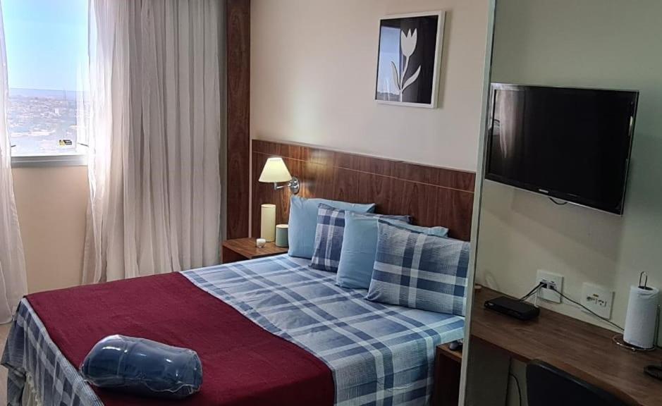 塔瓜汀加Lindo Flat Aconchegante no Centro de Taguatinga的酒店客房,配有床和电视
