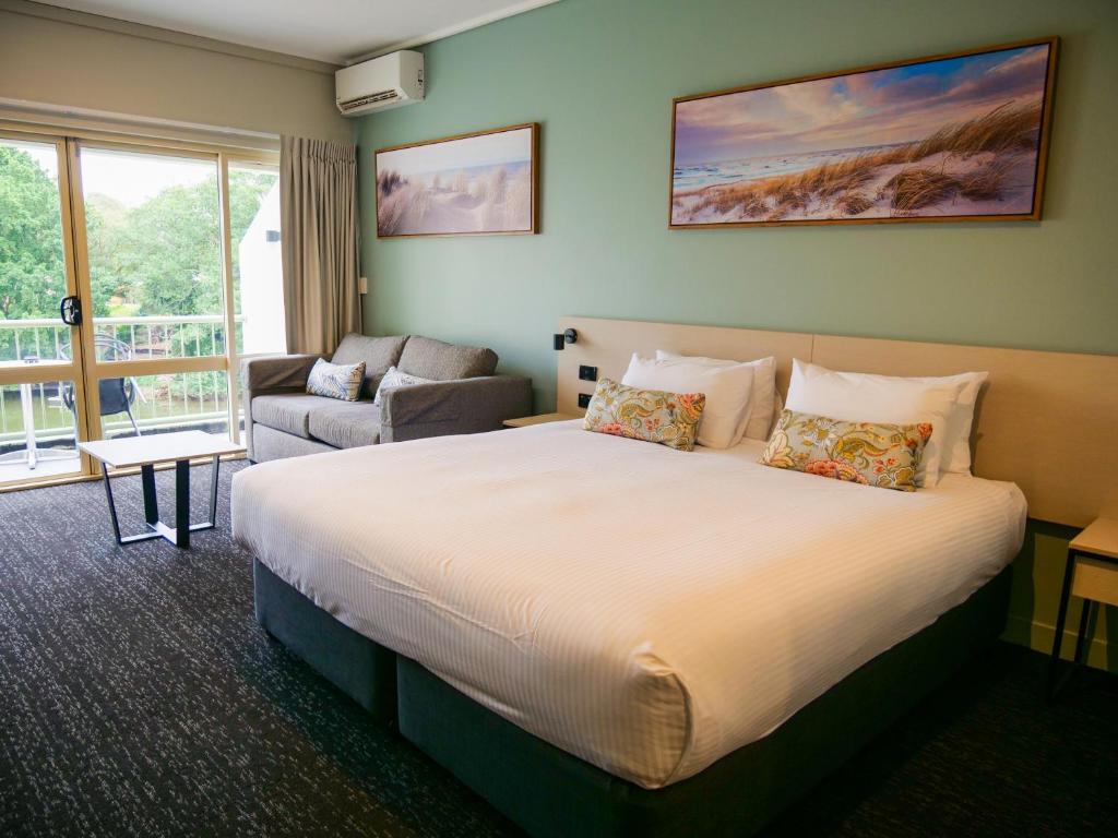 黄金海岸Nightcap at Hinterland Hotel Nerang的酒店客房设有一张大床和一张沙发。