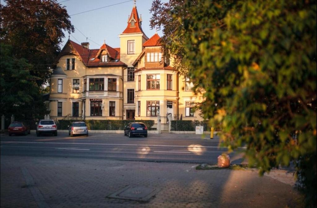 索波特Sopot Retro Apartment的一座大型建筑,前面有汽车停放