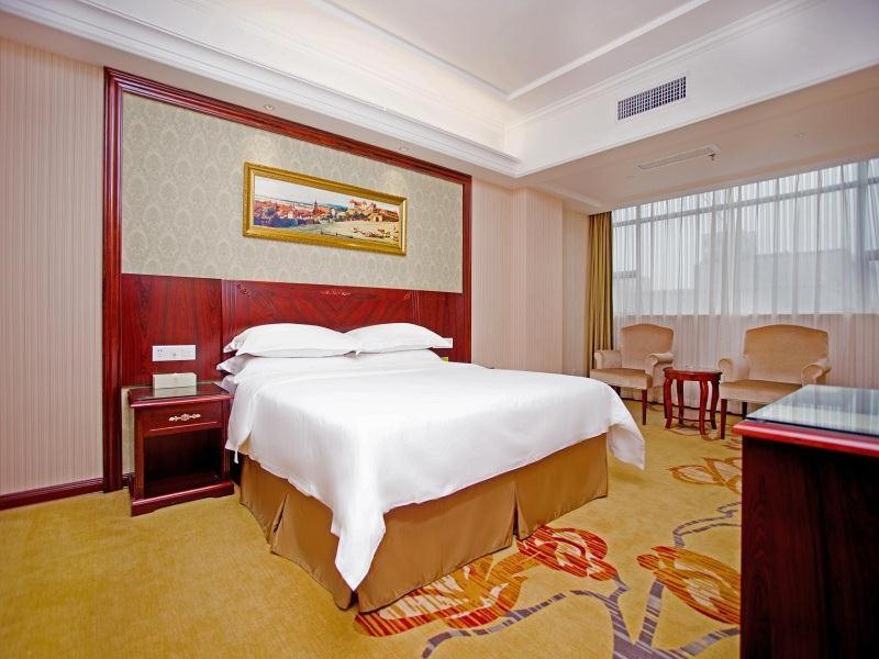 宝安维也纳酒店深圳石岩石龙社区店的酒店客房设有一张大床和一张桌子。