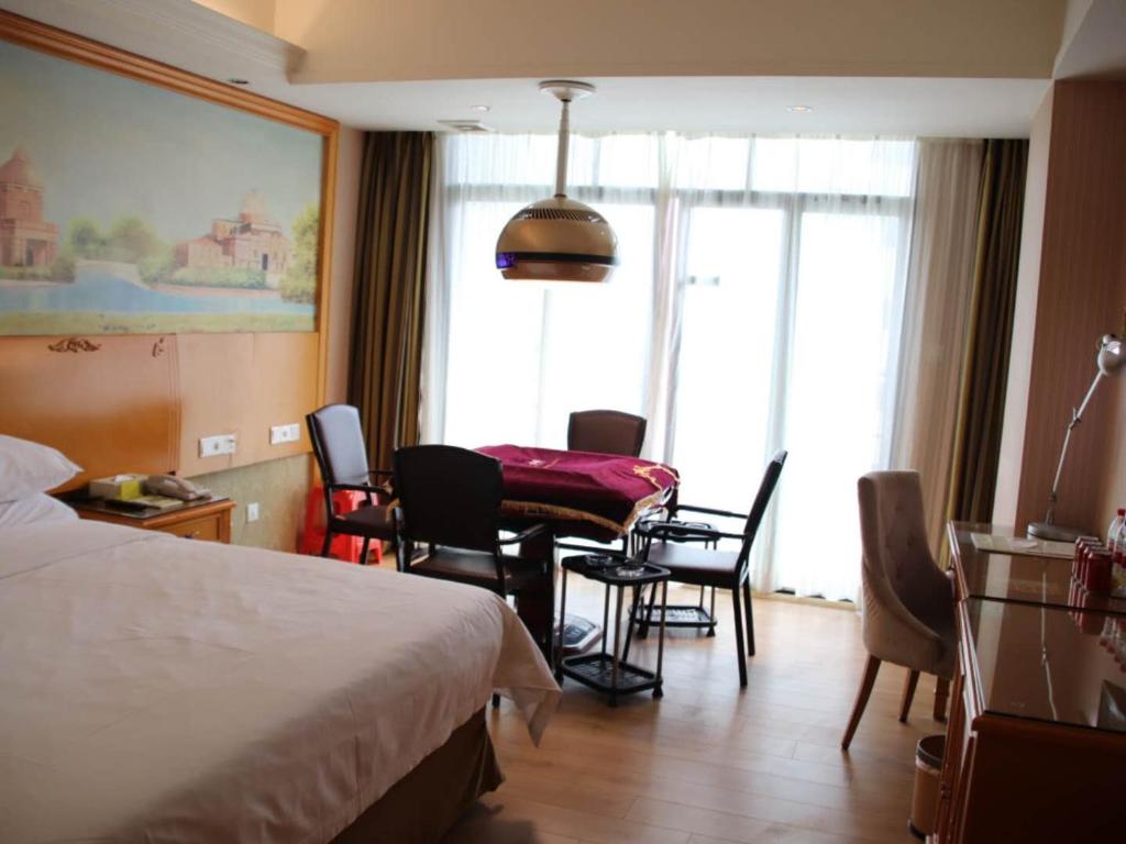 Yuanzhou维也纳酒店广东惠州园洲店的酒店客房带一张床、一张桌子和椅子