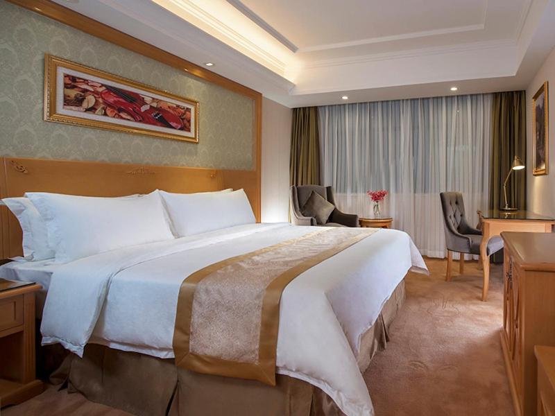 广州维也纳酒店广州番禺大石桥店的酒店客房设有一张大床和一张书桌。