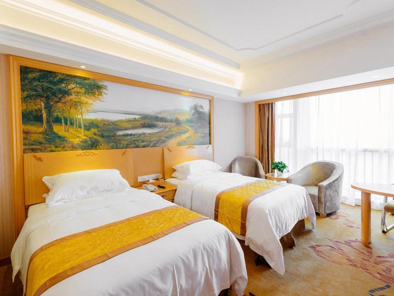 Nianbalian维也纳国际酒店上海滴水湖海洋公园店的酒店客房设有两张床,墙上挂有绘画作品