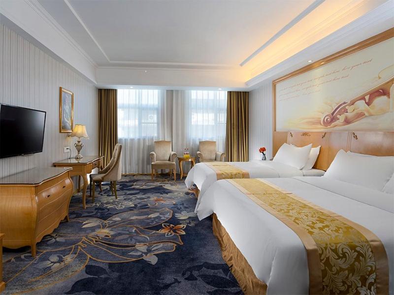 梅州维也纳酒店广东梅州江南店的酒店客房配有两张床和一张书桌