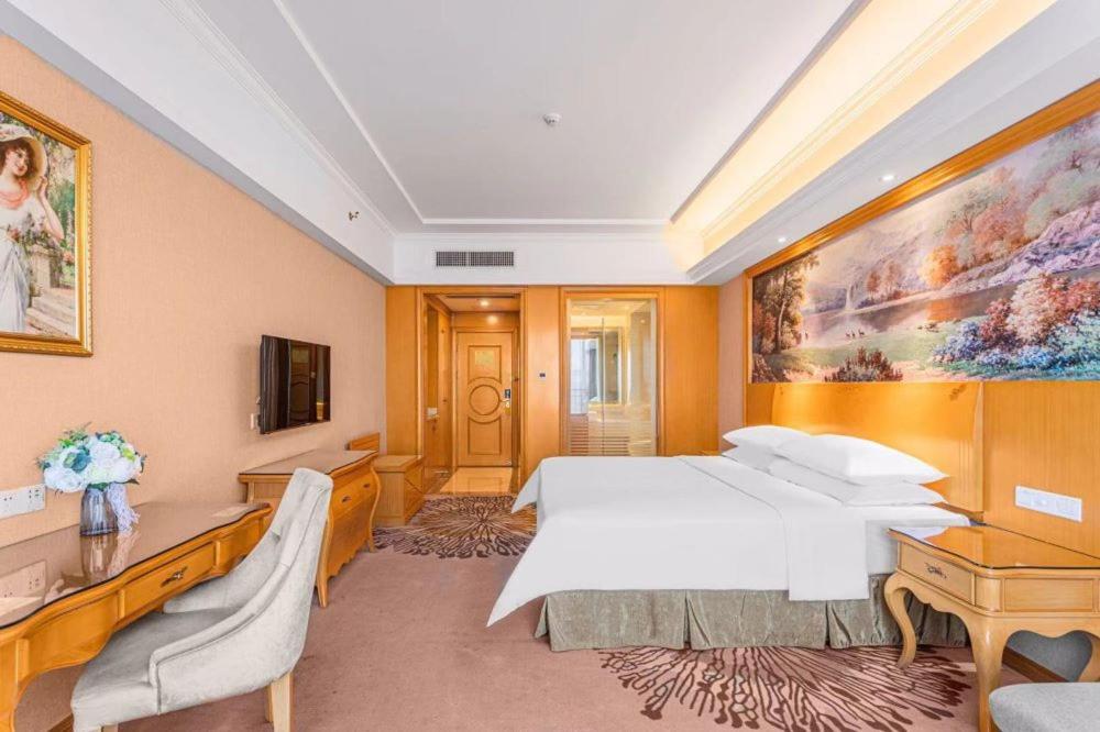 佛山维也纳酒店佛山罗村机场店的酒店客房设有一张床,墙上挂有绘画作品