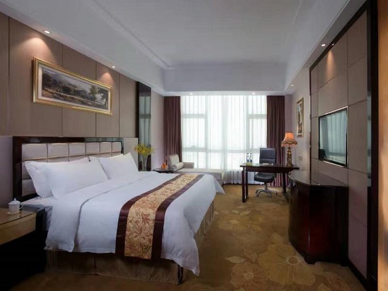 中山维也纳国际酒店广东中山北站店的一间卧室配有一张大床和电视
