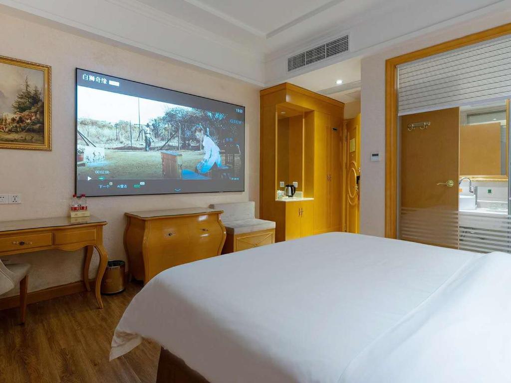 广州维也纳酒店广州北京路店的卧室配有壁挂式大屏幕平面电视。