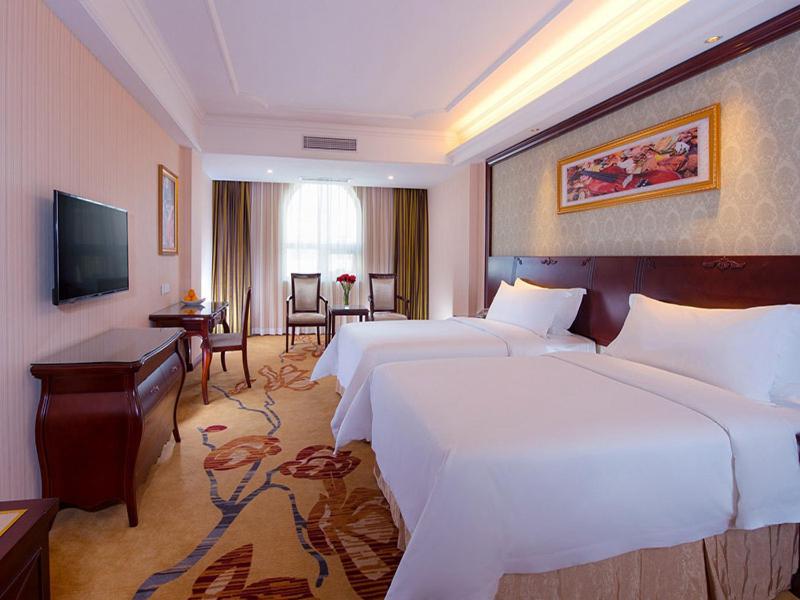 花都维也纳酒店广州狮岭店的酒店客房配有两张床和一张书桌