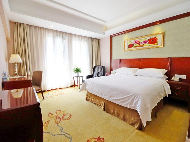 上海维也纳酒店上海虹桥国家会展纪翟路店的一间酒店客房,设有一张大床和一个大窗户