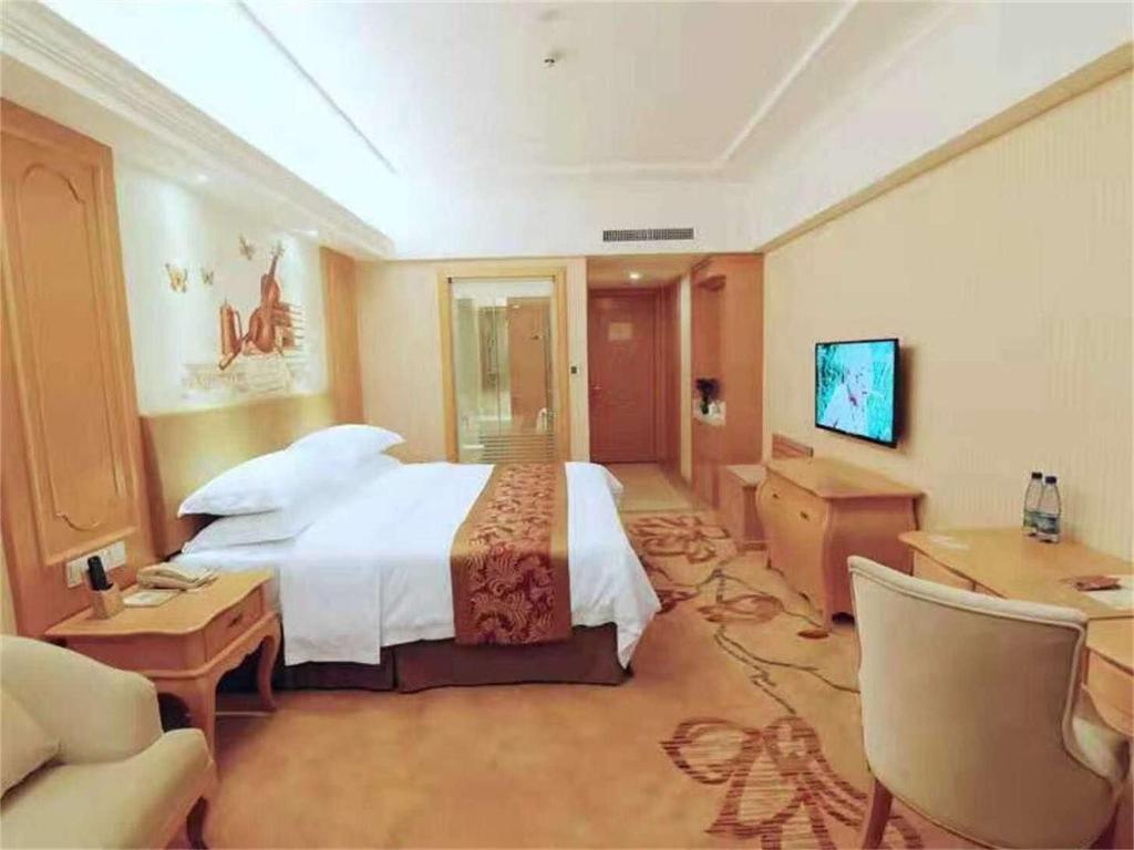 Guzhuting维也纳酒店湖南永州冷水滩区政府广场店的大型酒店客房,配有一张床和一张书桌