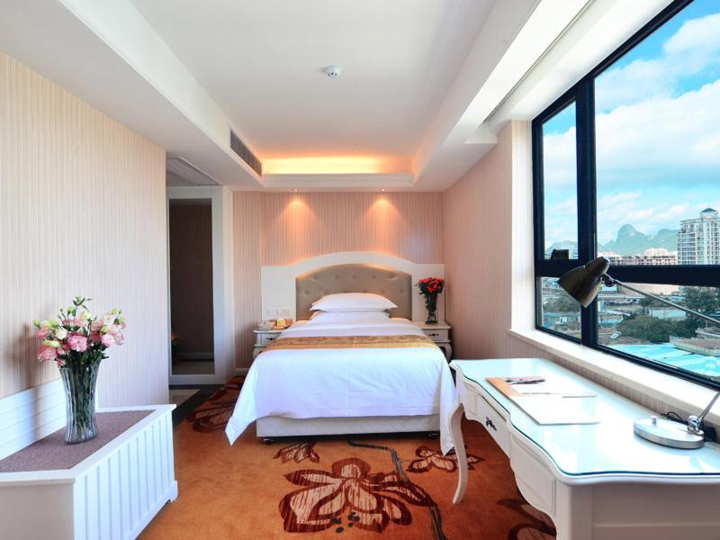 桂林维也纳酒店广西桂林站店的一间卧室配有一张床、一张书桌和一个窗户。