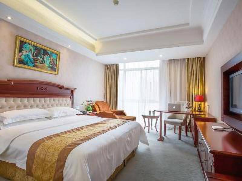 苏州维也纳酒店苏州乐园店的酒店客房设有一张大床和一张书桌。