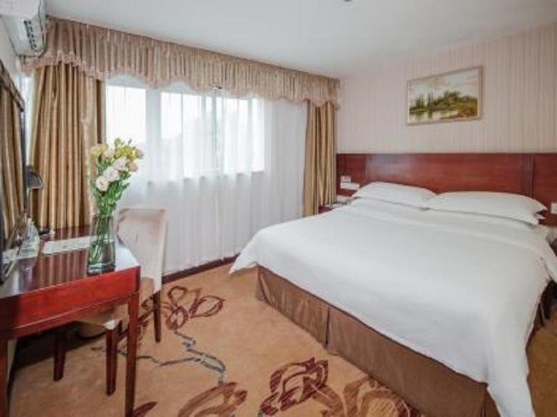 宝安维也纳3好店深圳观澜高尔夫店的一间卧室配有一张大床、一张书桌和一个窗户。