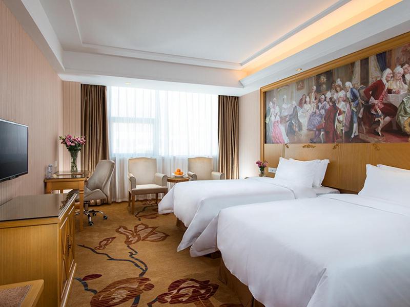 宝安维也纳3好酒店深圳龙华大浪商业中心店的一间酒店客房,设有三张床和一台平面电视