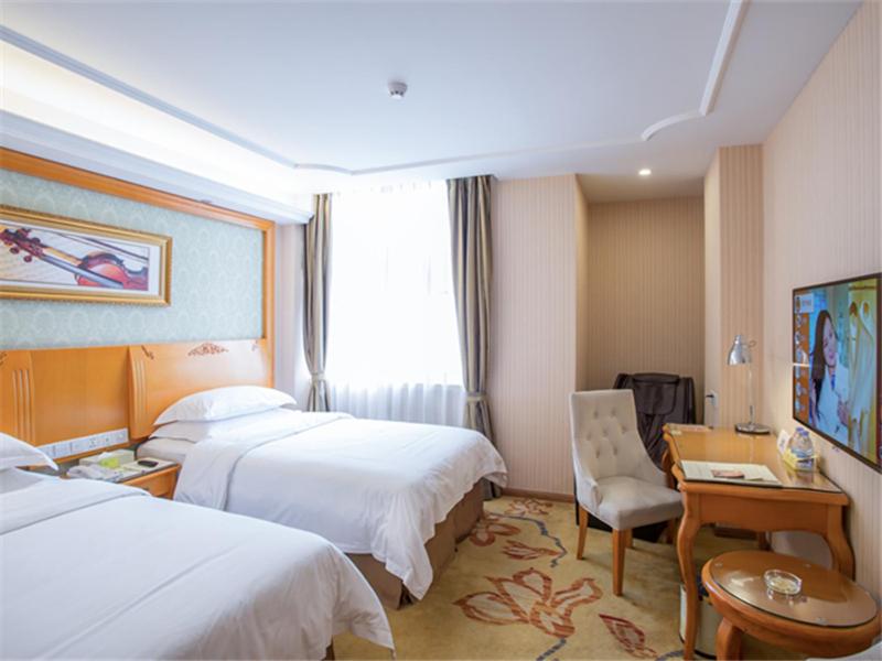 广州维也纳酒店广州南浦地铁站店的酒店客房配有两张床和一张书桌
