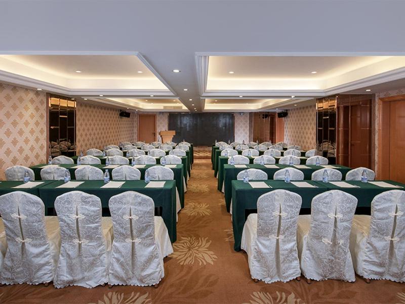 广州维也纳酒店广州天河客运站店的宴会厅配有绿色和白色的桌椅