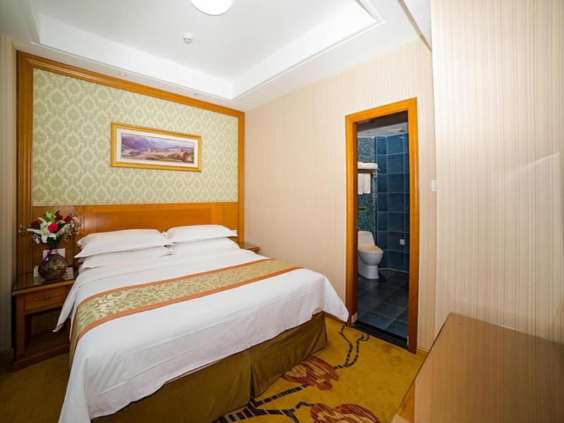 烟台维也纳酒店山东烟台金沙滩泰山路店的一间带大床的卧室和一间浴室