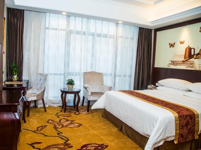 杭州维也纳国际酒店 (杭州下沙大学城店)的酒店客房带一张床、一张桌子和椅子