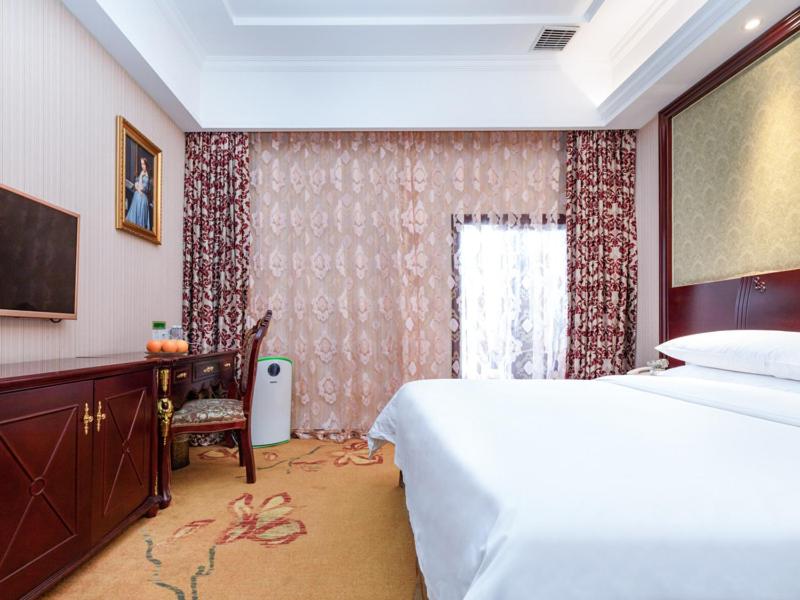 松江维也纳酒店上海松江万达店的一间卧室配有一张床、一张书桌和一个窗户。