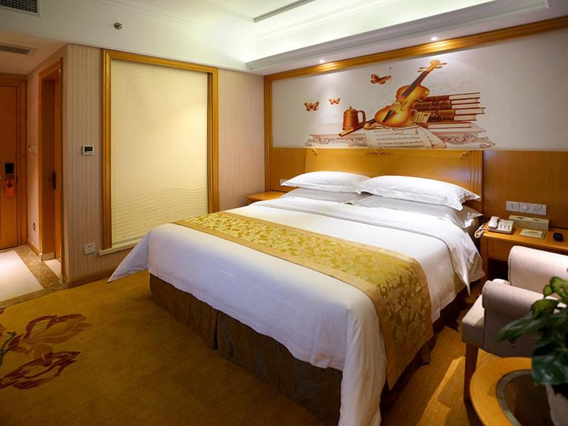 青浦维也纳酒店上海虹桥国展中心华新店的卧室配有一张大床,墙上挂着小提琴