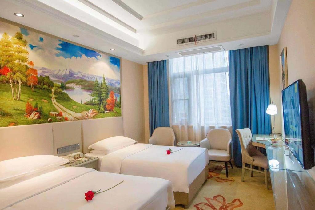 南阳维也纳酒店南阳人民路店的酒店客房设有两张床,墙上挂有绘画作品