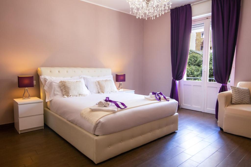卡利亚里Arcobaleno Suites的一间卧室配有一张带紫色窗帘和吊灯的床。