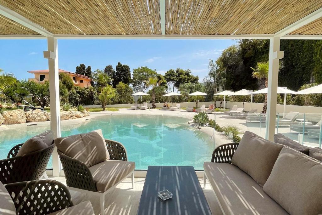 圣多米尼卡Suite Hotel L'Oasi di Riaci的庭院设有带椅子和桌子的游泳池。