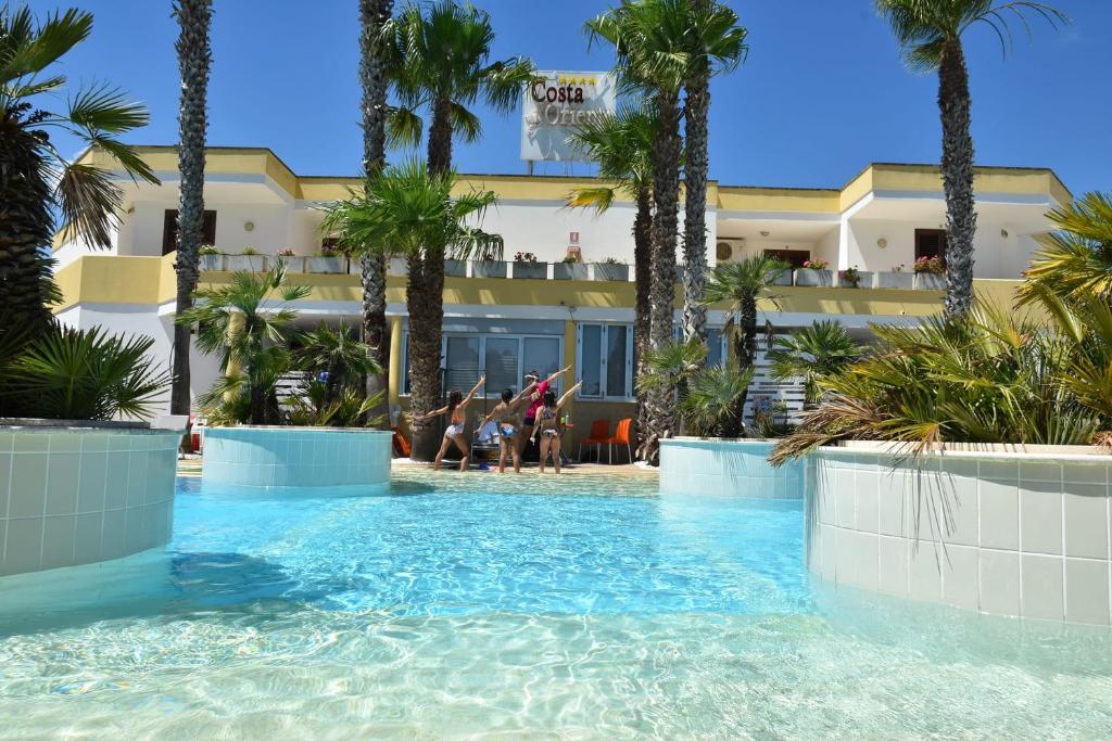 托里德欧索Residence Club Costa D'Oriente的棕榈树酒店前的游泳池