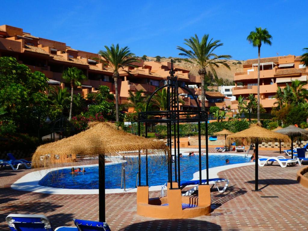 阿尔梅利马Apartamentos Almerimar Golf的一个带椅子和遮阳伞的游泳池的度假酒店