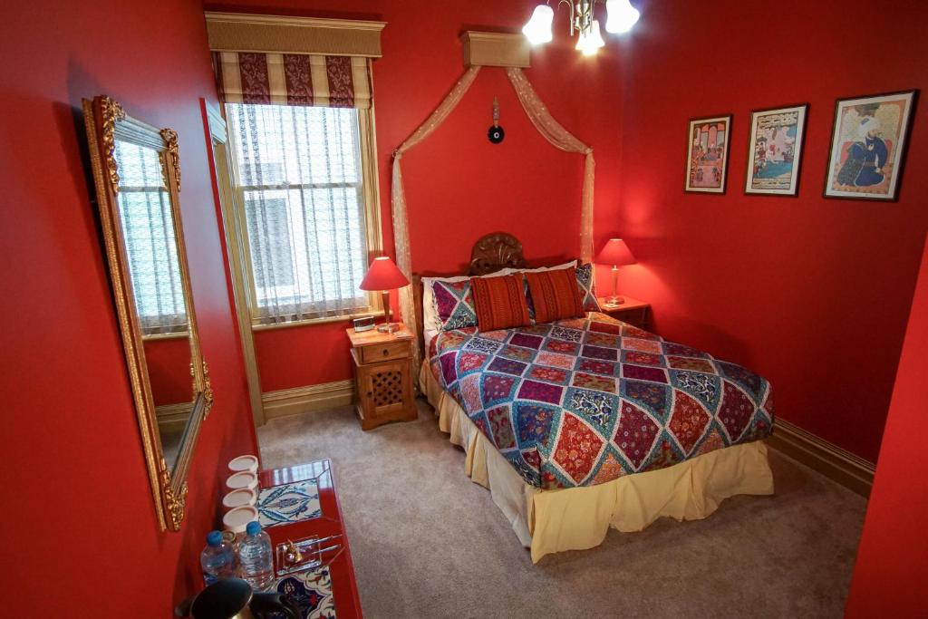 纳皮尔Sea Breeze B & B的一间卧室设有红色的墙壁和一张带镜子的床