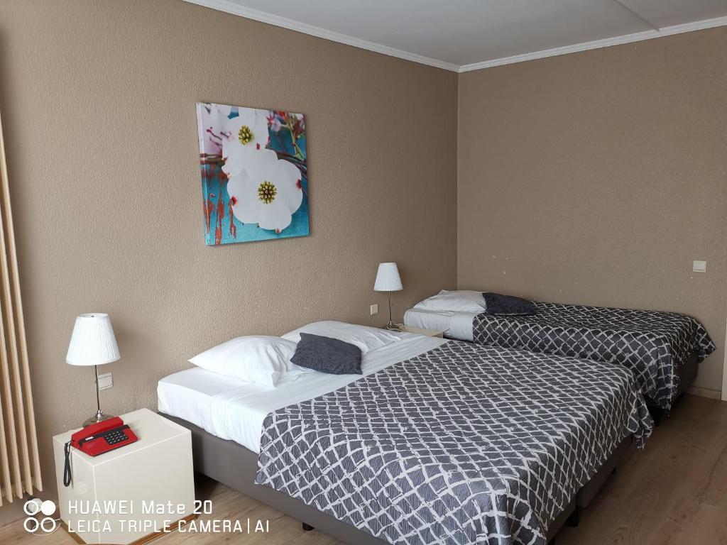 菲利普维尔Hôtel La Côte d'Or的酒店客房设有两张床,墙上挂有绘画作品