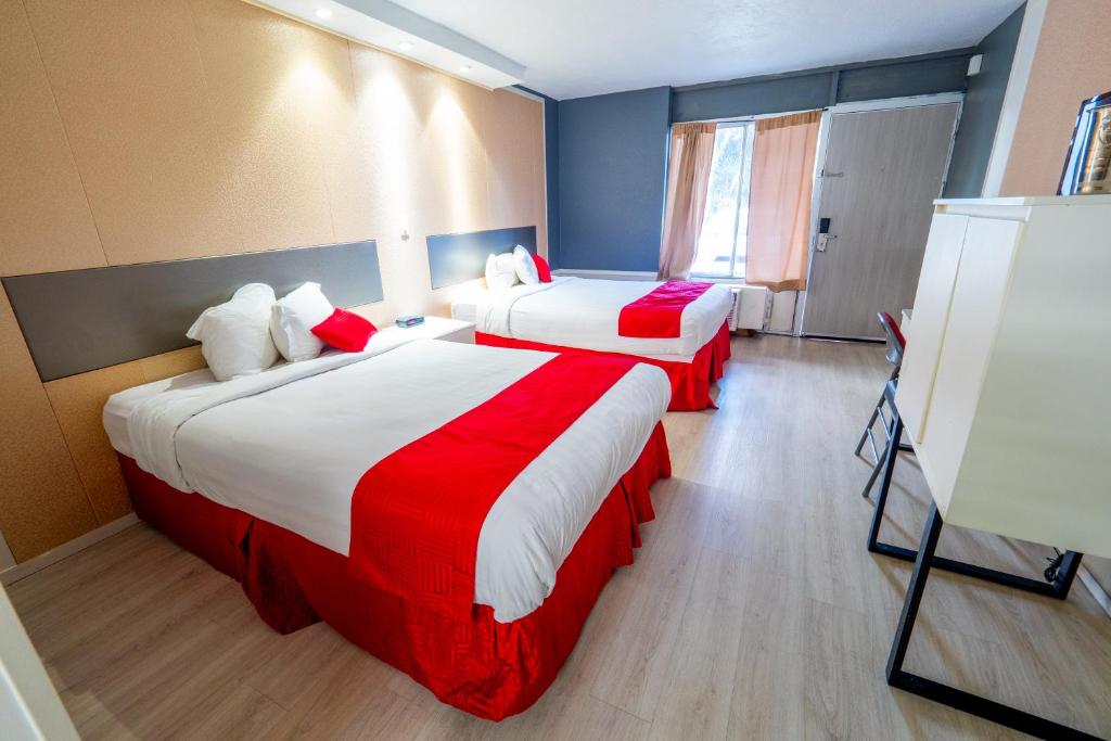 奥兰多Travelodge by Wyndham Orlando at Heart of International Drive的酒店客房带两张红色和白色的床单