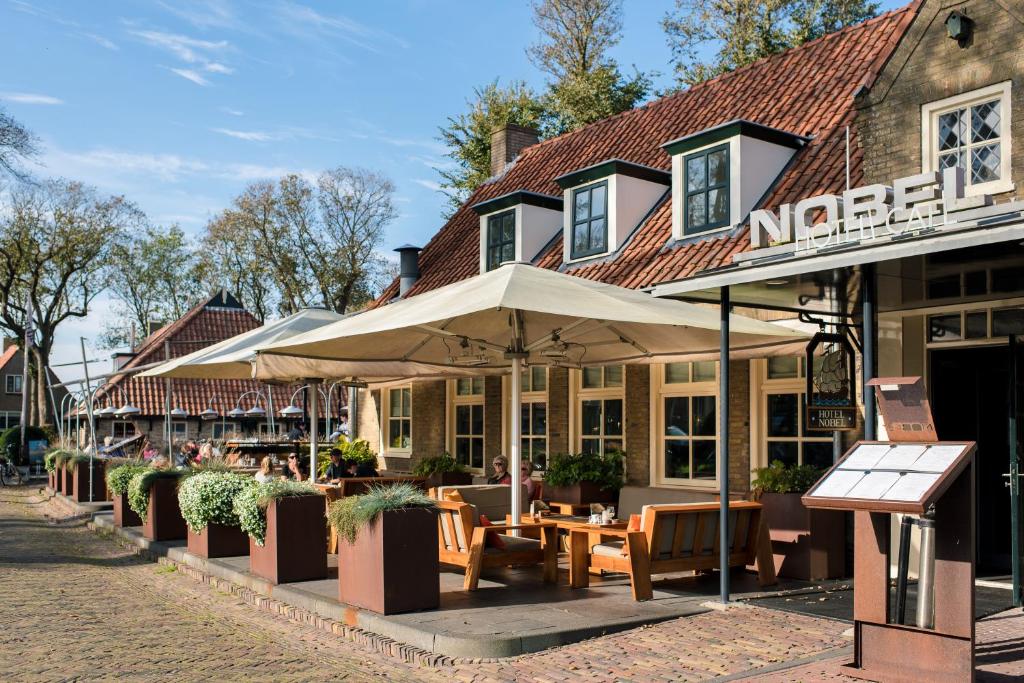 巴勒姆Nobel Hotel Ameland的街边设有桌子和遮阳伞的餐厅