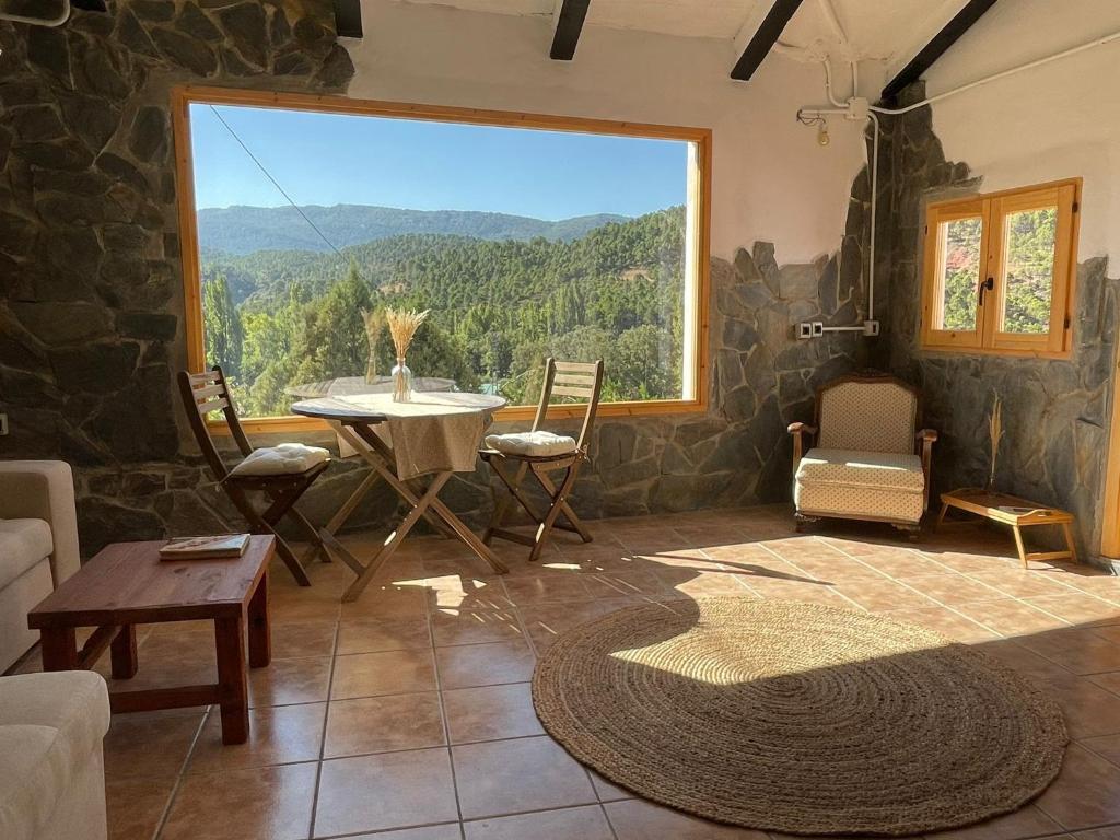 里奥帕尔Casa Rural El Carrizal的客厅设有桌子和大窗户