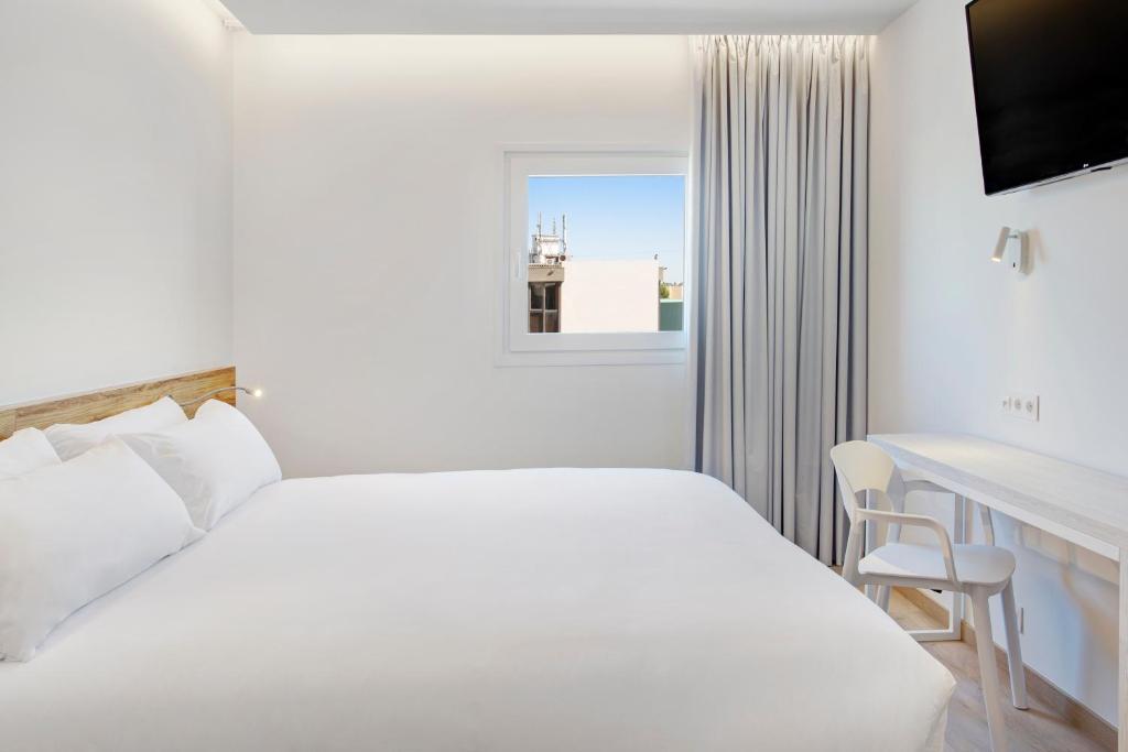 马托西纽什B&B HOTEL Porto Expo Aeroporto的白色的卧室设有床、书桌和窗户