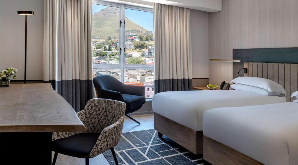 开普敦Hyatt Regency Cape Town的酒店客房带两张床和一张桌子以及椅子。