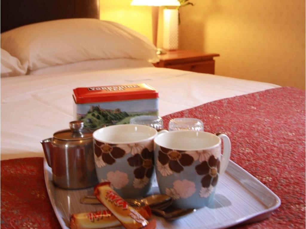 哈罗盖特美利楼酒店的床上的托盘,上面有两个咖啡杯