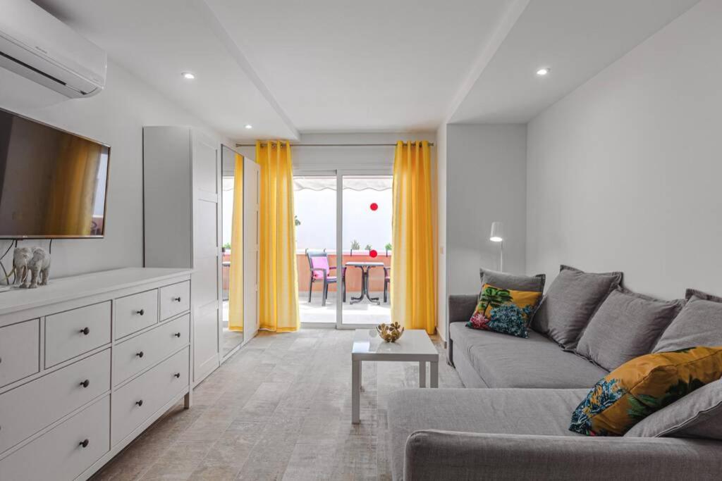 美洲海滩Tenerife Royal Gardens One Bedroom Apartment的客厅配有灰色的沙发和黄色的窗帘
